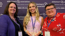 A photo of (from left to right) Jen McAlister, Olivia Deering and Bonnie Nuttkinson at the Alzheimer's Association Wisconsin Chapter's State Conference. Deering holds an award in her hands. All three smile at the camera