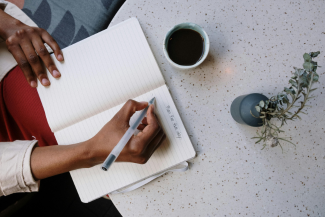 Person sitting at a table with a cup of coffee making a plan for the day