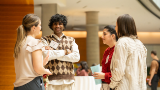 Four researchers stand in a circle and chat at ADRD Research Day 2025