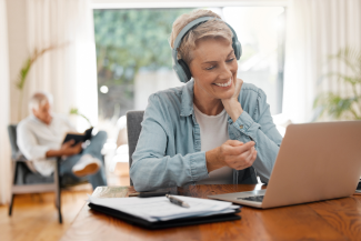 Person participating in a Zoom meeting on their laptop with headphones on.