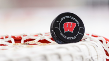 A hockey puck with the UW-Madison Athletics 'W' logo on it