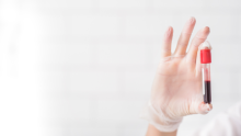 Gloved hand holding a vial of blood