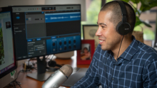 Dr. Nathaniel Chin sits before two computer monitors and a microphone to record an interview